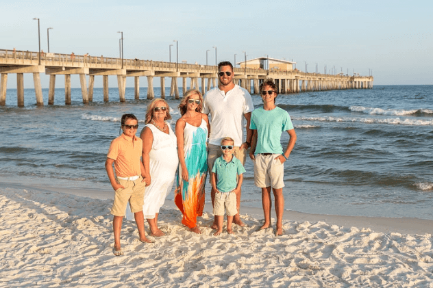 Family portrait on sandy beach near pier at golden hour