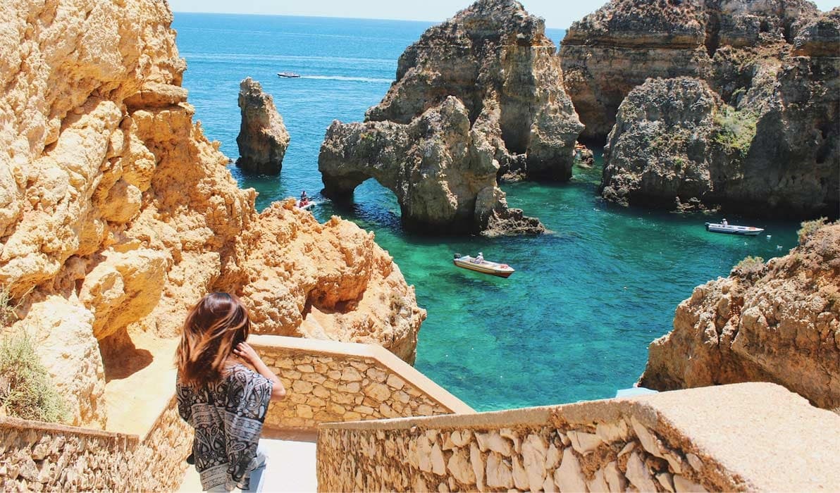 Cliffside hiker overlooking turquoise sea and limestone rock formations
