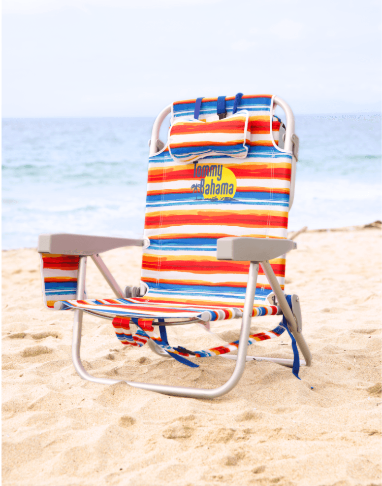 Two blue beach chairs under umbrella on sandy coastline