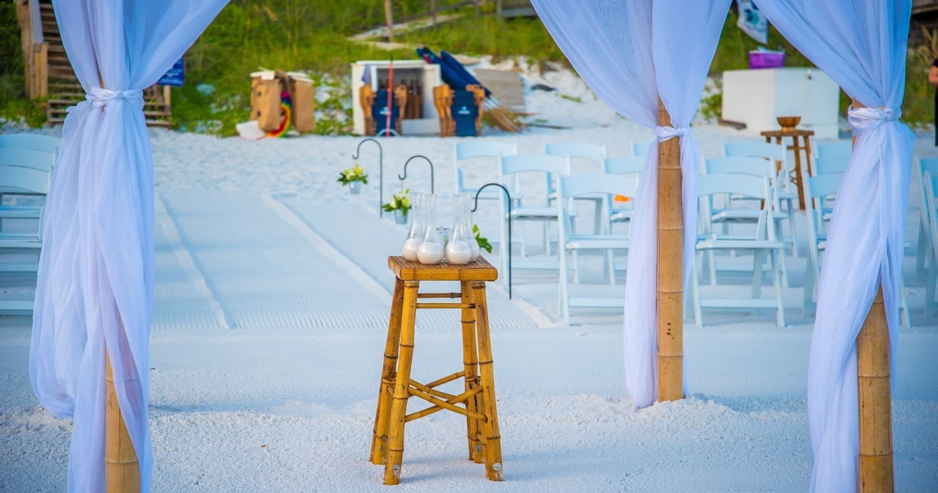 Decorated beach wedding arch with chairs on white sand