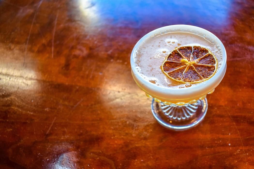 Artisan cocktail on wooden bar, craft drink tasting during tour