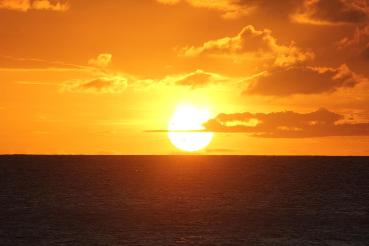 Golden sunset over open ocean, peaceful sailing sunset vista