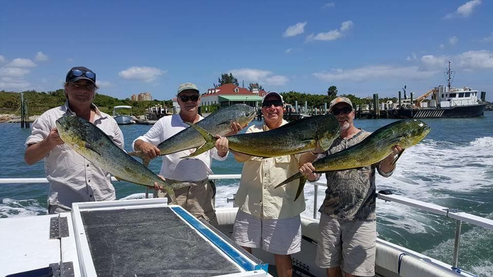 Group of anglers holding dolphinfish (mahi) on boat offshore