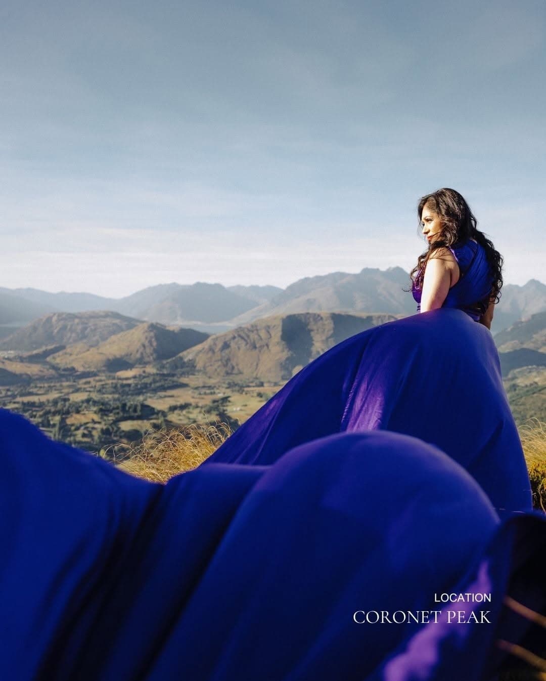 Woman in royal blue gown on alpine ridge with valley vista