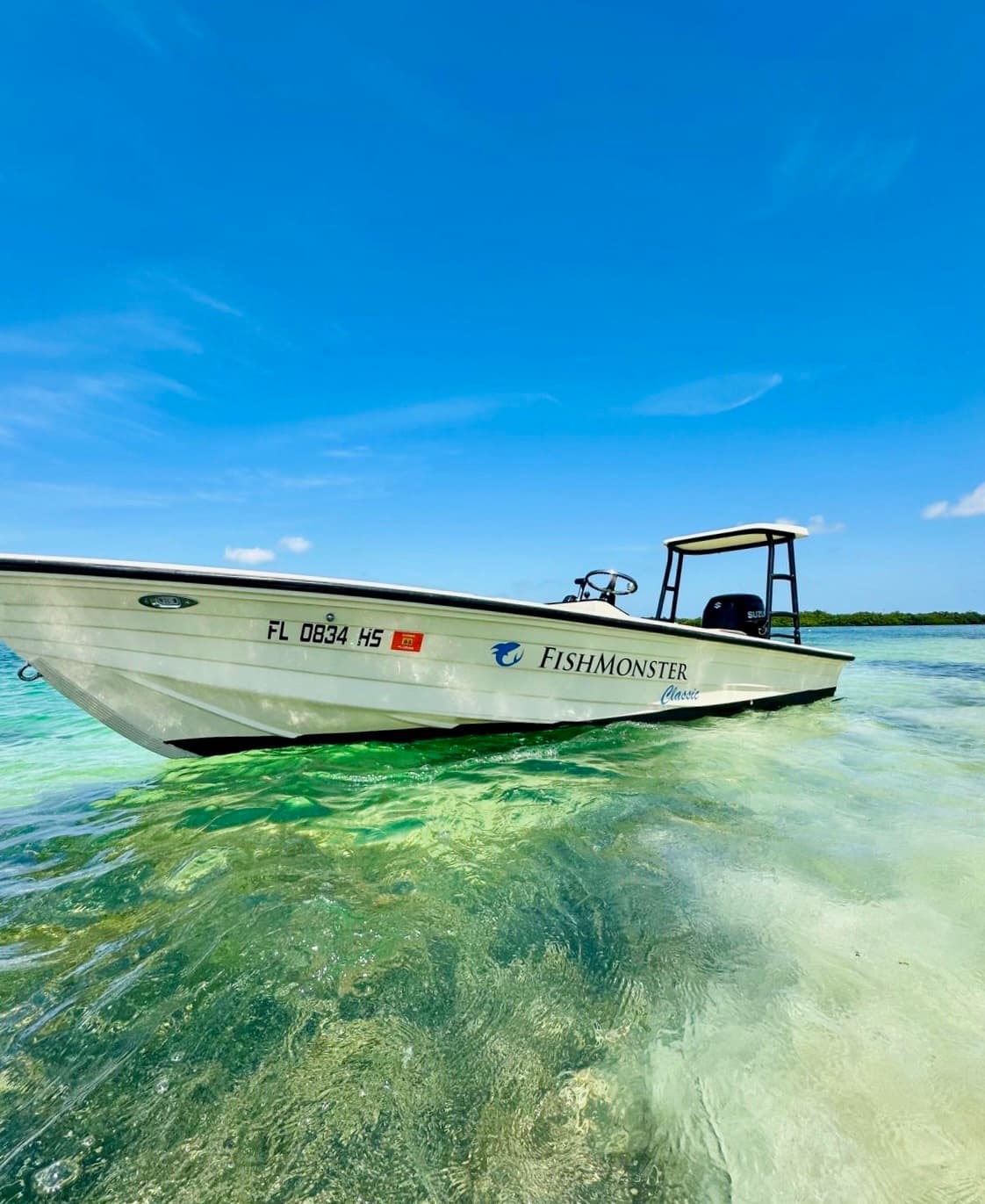 Shallow-water skiff moored over crystal turquoise flats, fishing