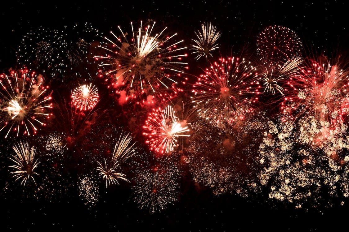 Red and gold fireworks over coastal skyline at night