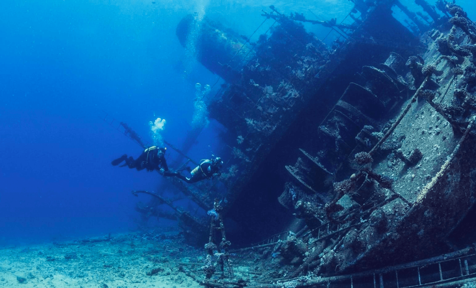 Diver exploring vibrant shipwreck on clear tropical reef