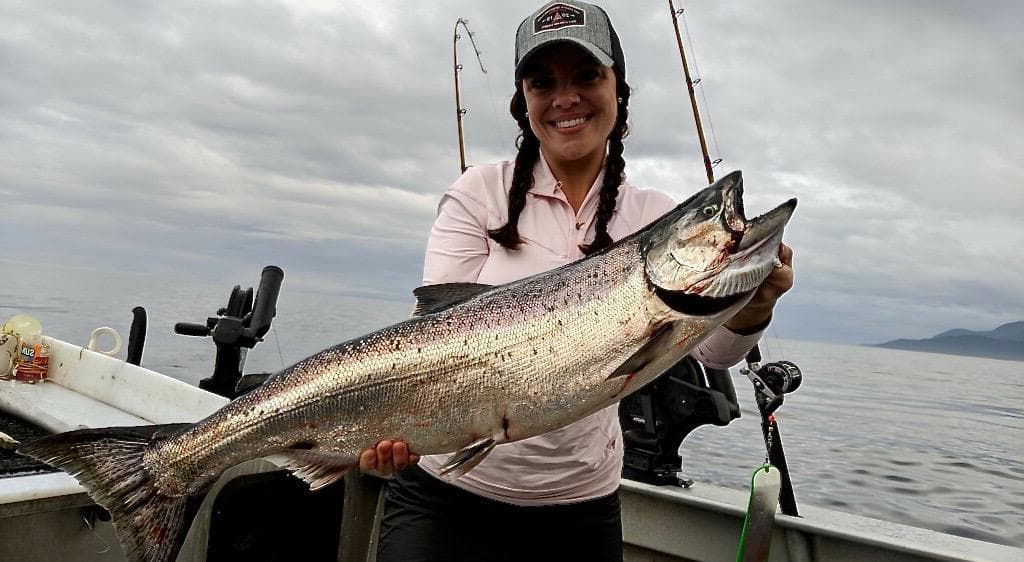 Angler holding large salmon on charter boat Gulf of Alaska