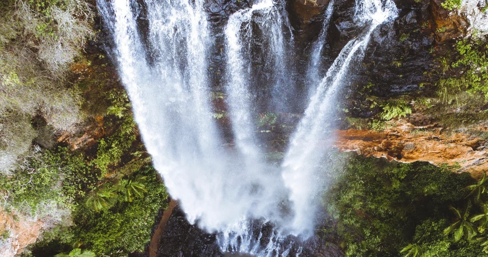 Powerful tropical waterfall cascading into rocky forest pool