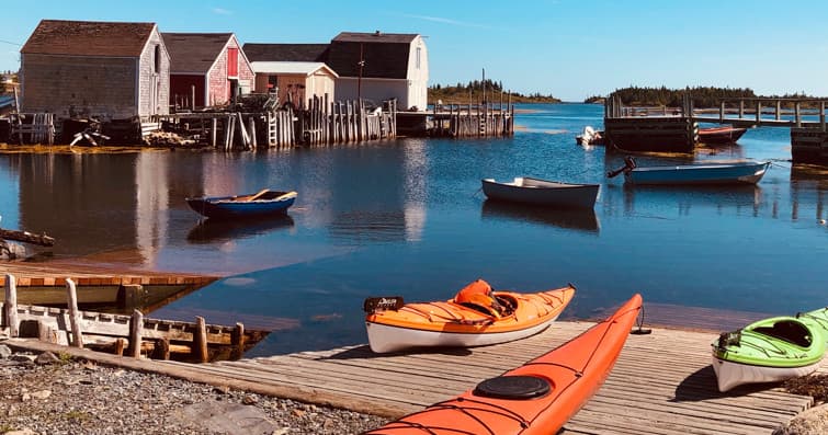 Kayaks on wooden dock at coastal fishing village, summer tour