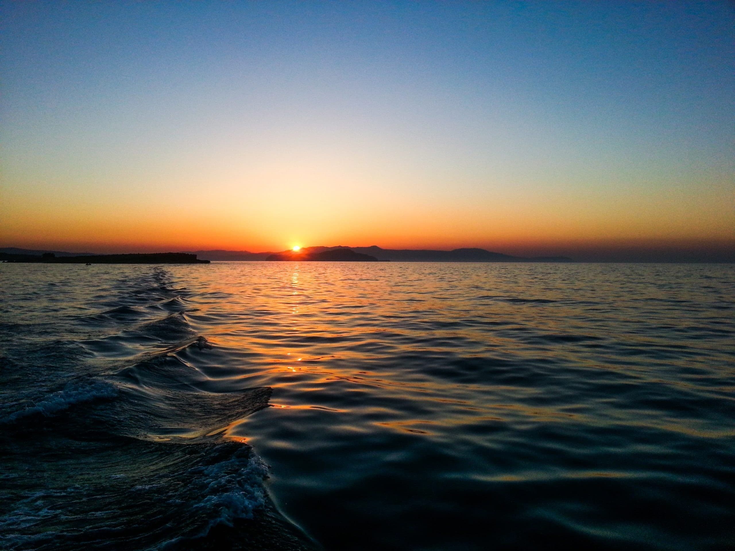 Boat wake leading to colorful sunset over open Mediterranean sea