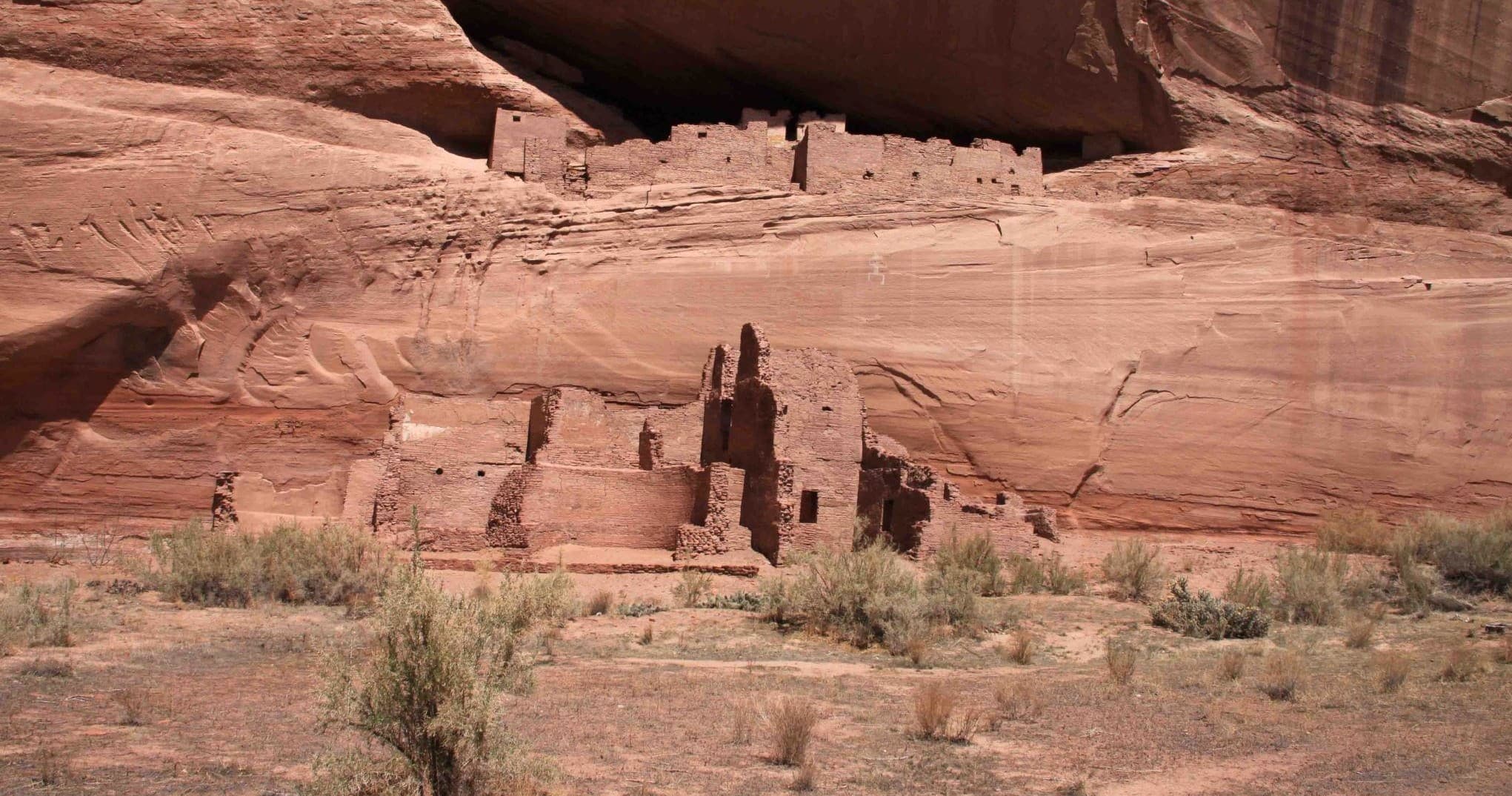 Ancient cliff dwellings carved into red rock canyon wall