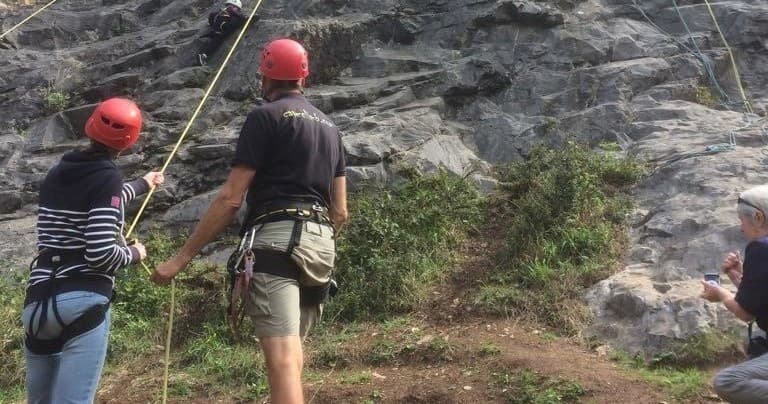 Rock climber being belayed on outdoor crag with instructor