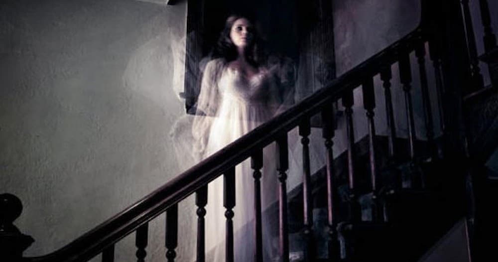 Apparition descending dim staircase inside haunted historic house tour