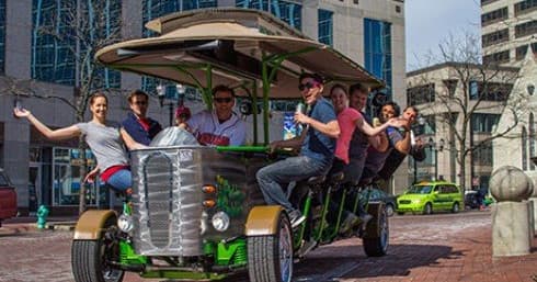 People enjoying a pedal pub tour in urban downtown street