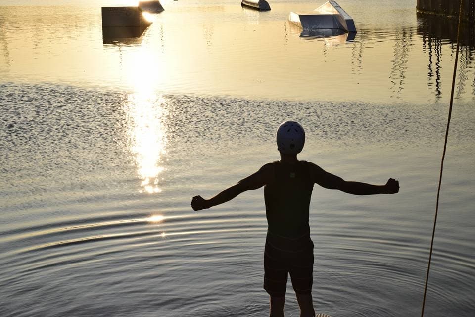 Silhouette swimmer stretching at sunrise over calm waterfront