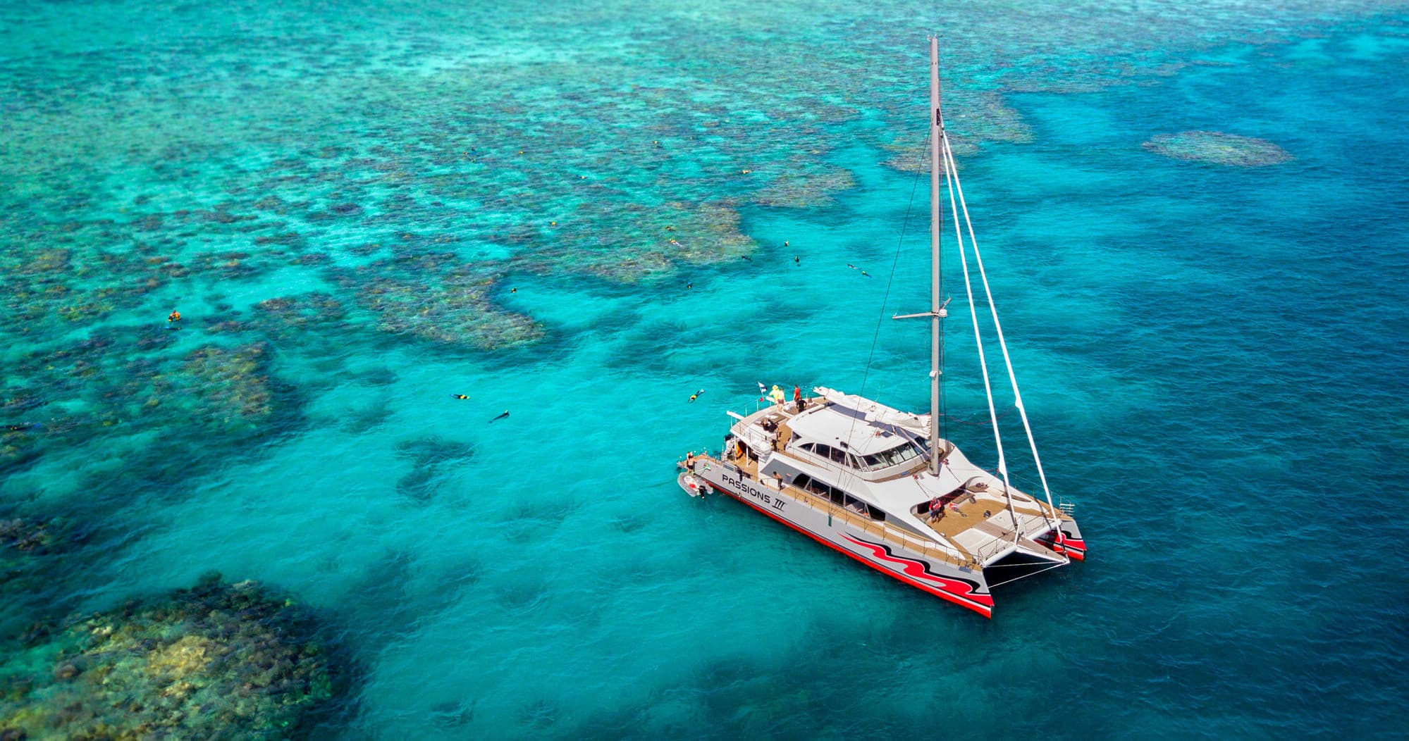 Catamaran anchored over turquoise reef in tropical waters