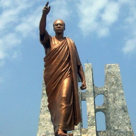 Bronze independence monument statue overlooking city plaza under sky
