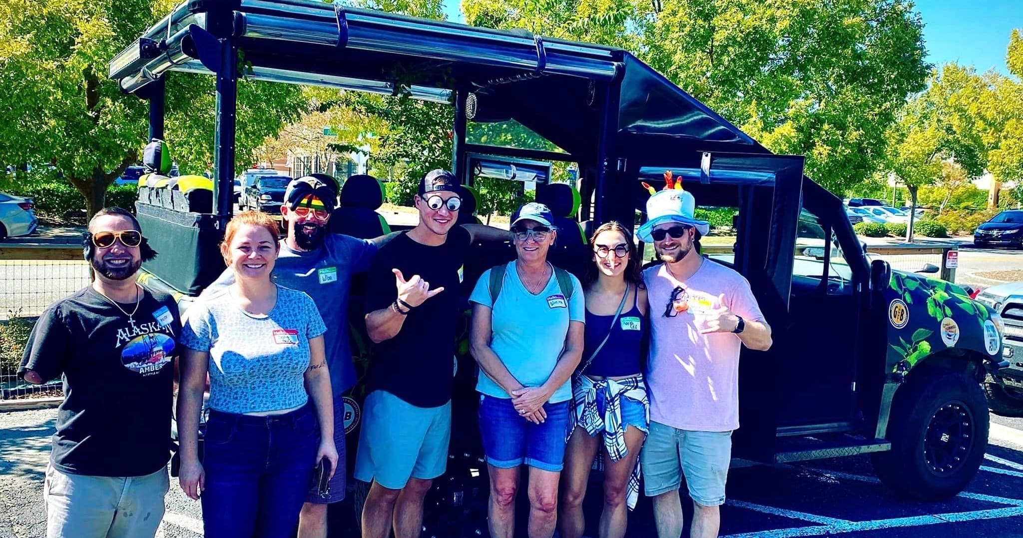 Group posing beside open-air adventure vehicle in sunny park