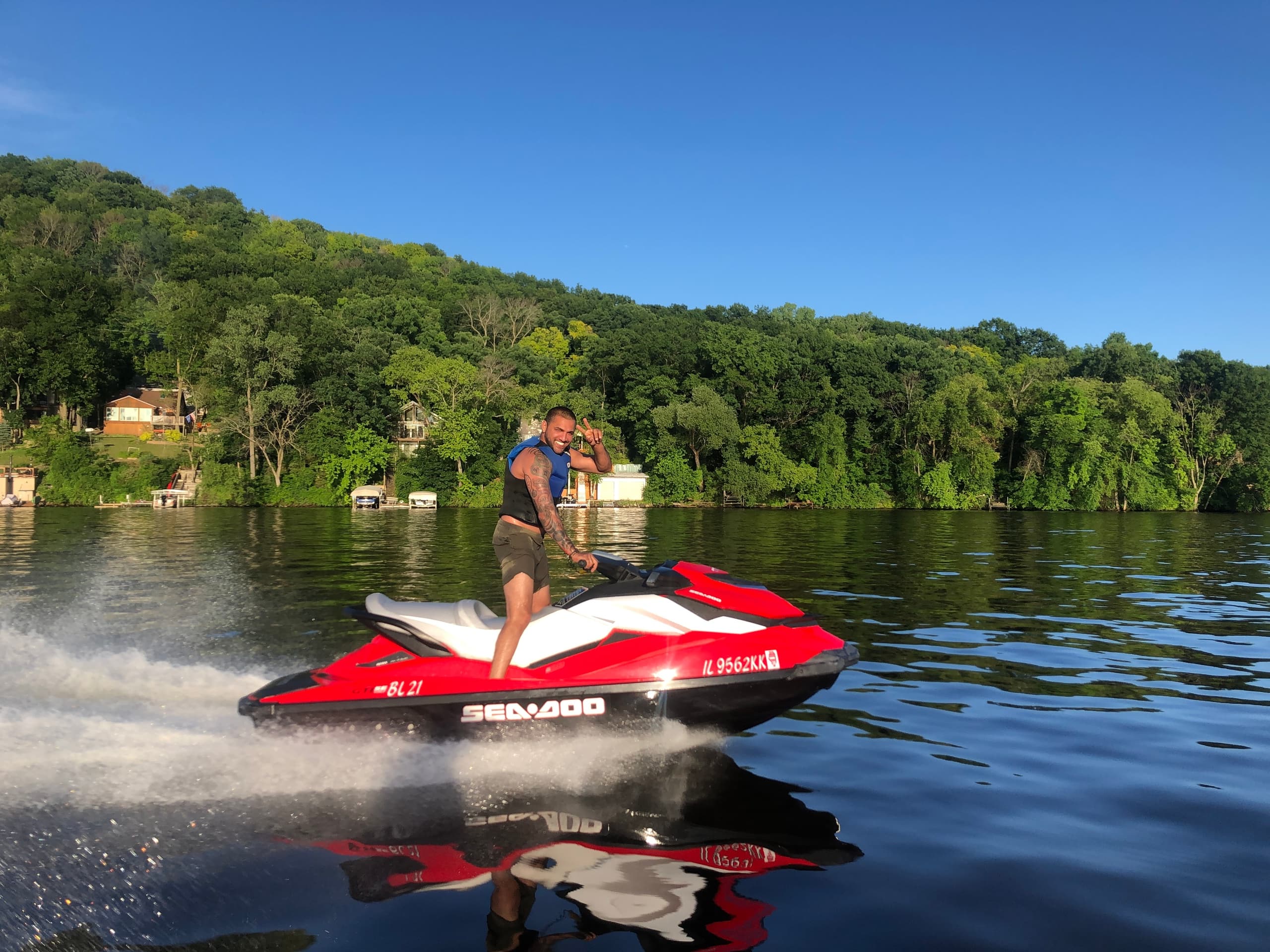 Rider on red jet ski skimming across reflective lake water