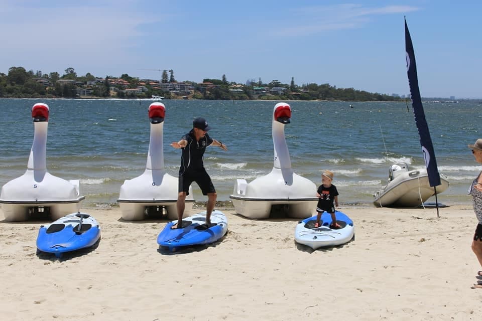 Swan pedalos and paddleboards on sunny sandy beach