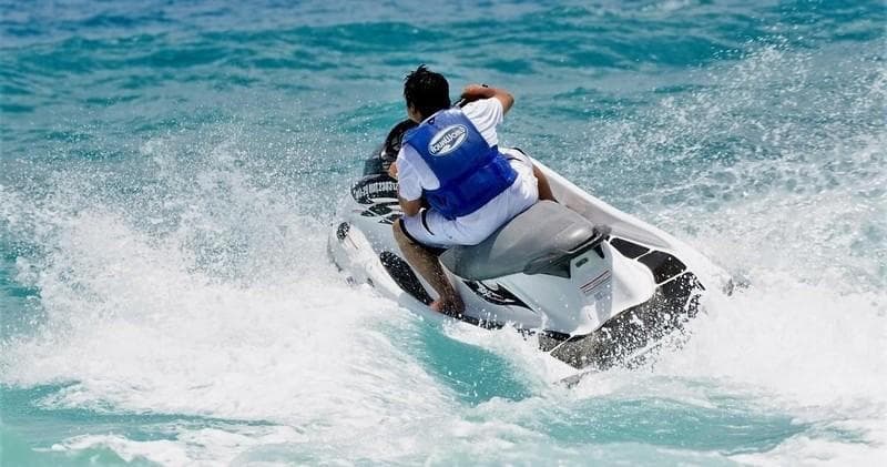 Jet skier racing across turquoise ocean waves near coastline