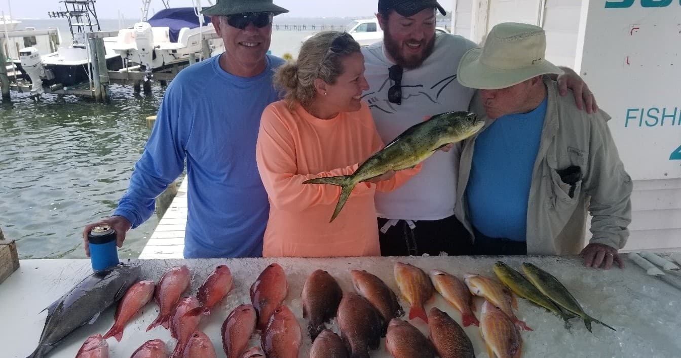 Anglers displaying varied snapper and mahi on dock after trip