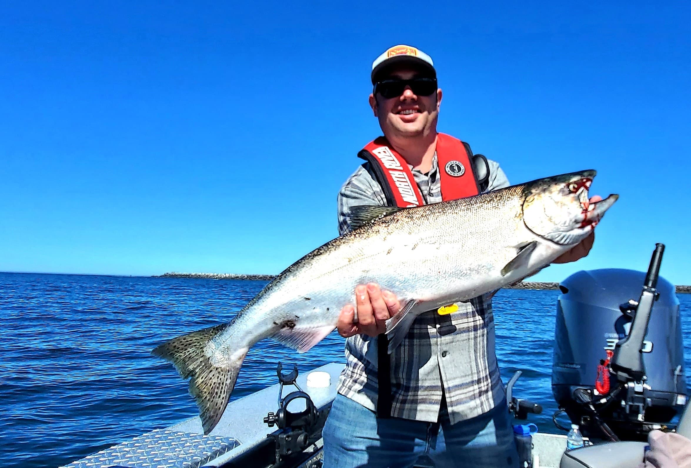 Angler holding large salmon on ocean boat off Pacific coast