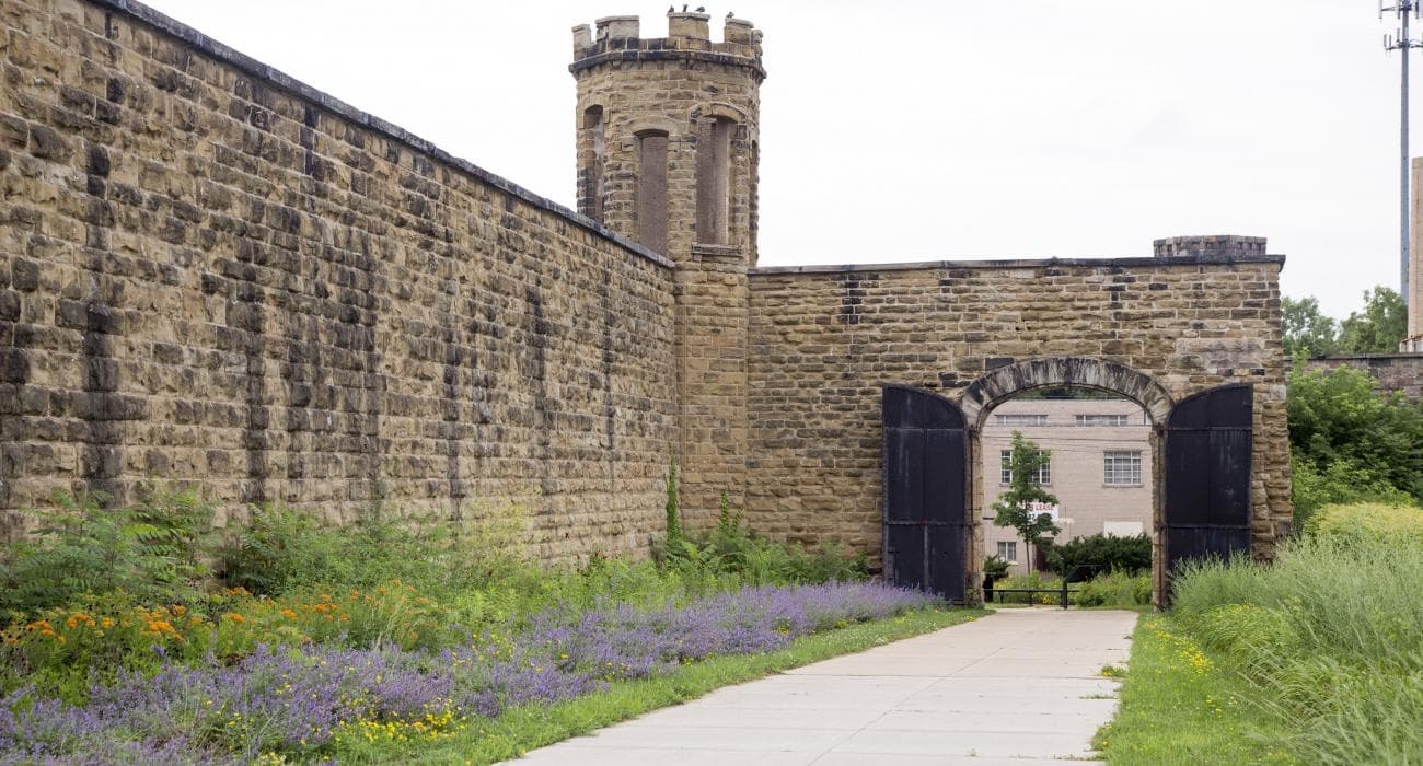 Visitors walking along historic prison exterior and gated entrance