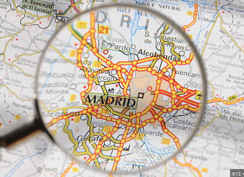 Magnifying glass over Madrid city map highlighting routes