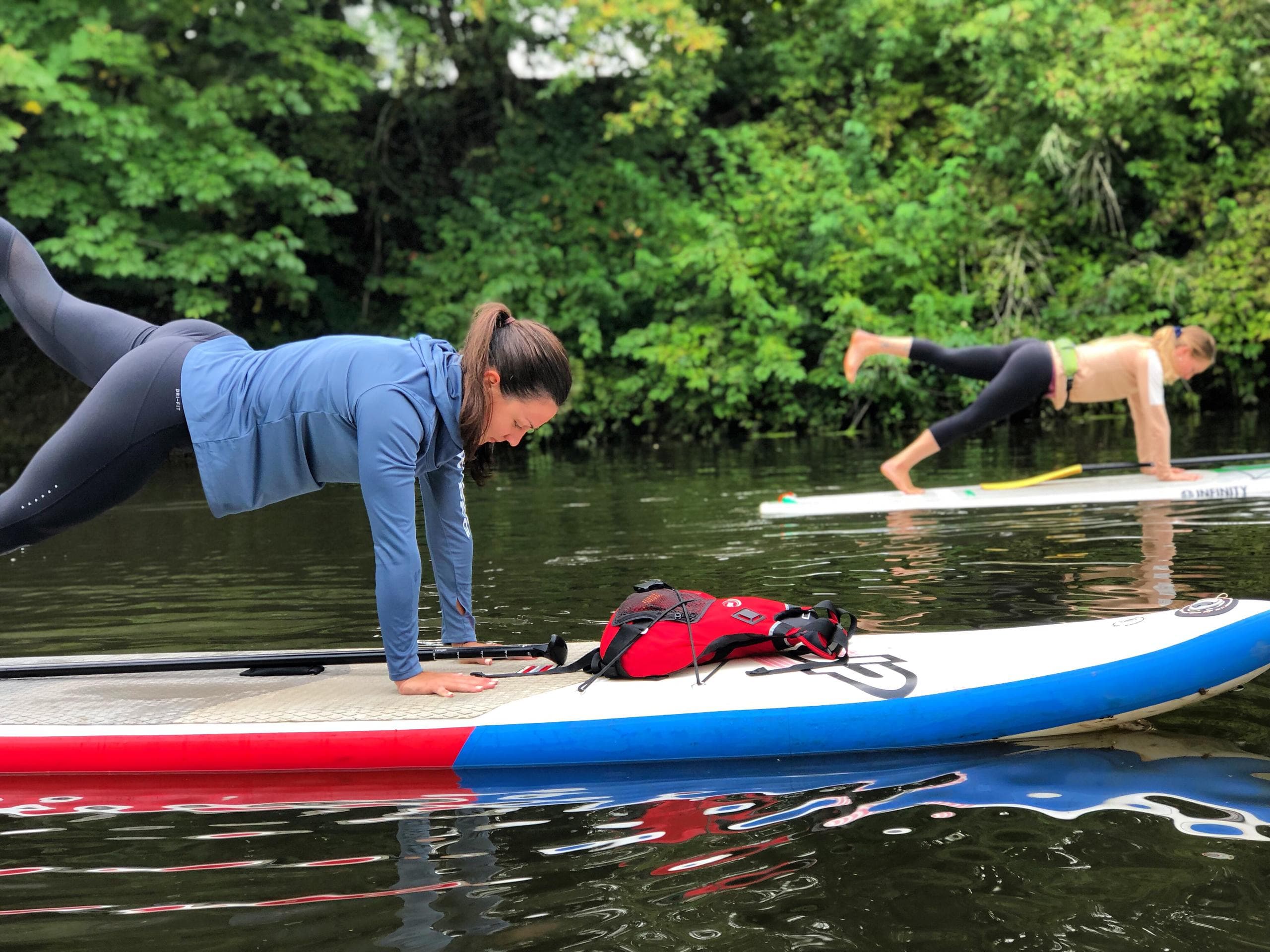 Outdoor paddleboard yoga class practicing planks on river