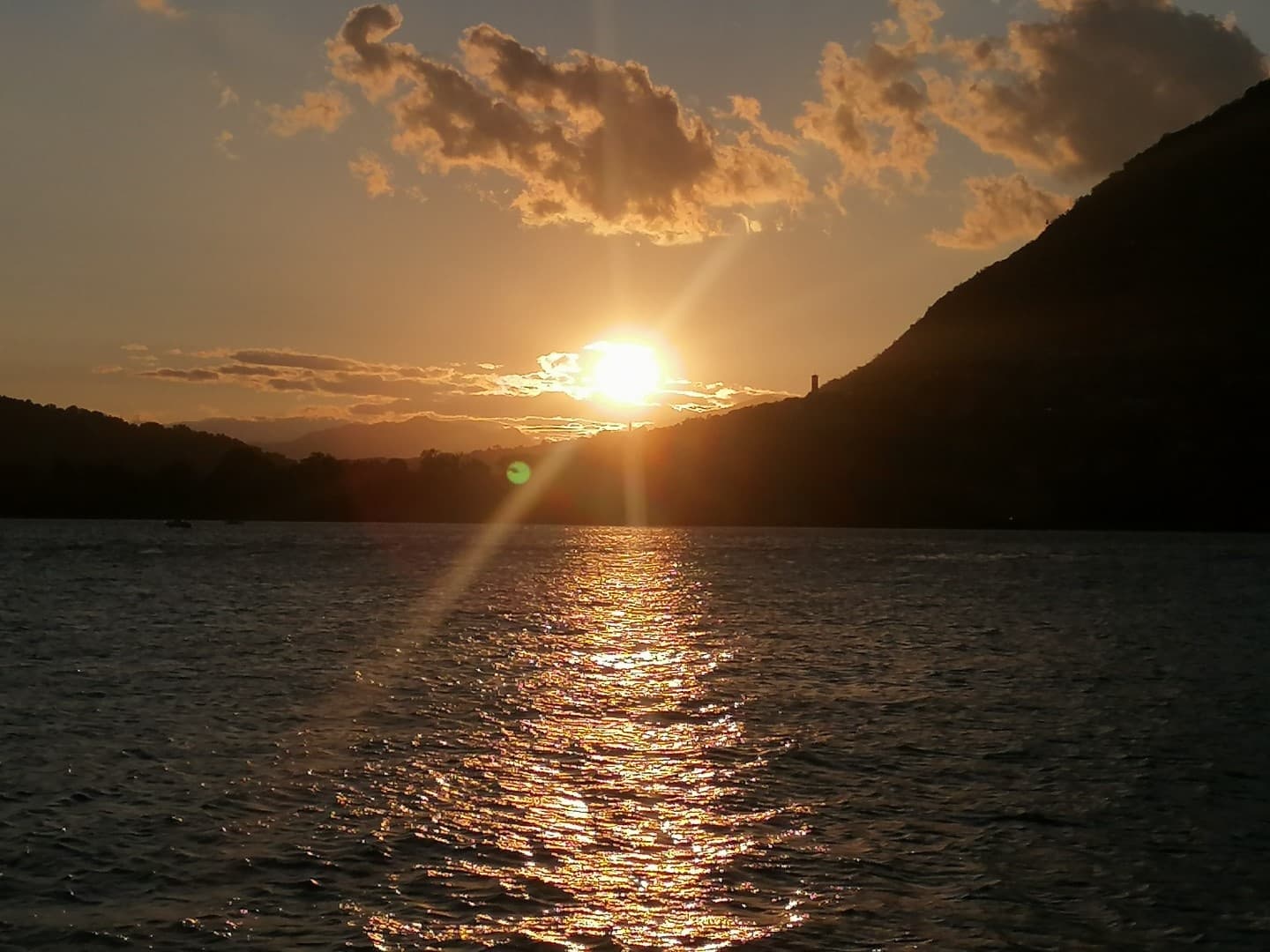 Sunset light and reflected sun across Lake Como water surface