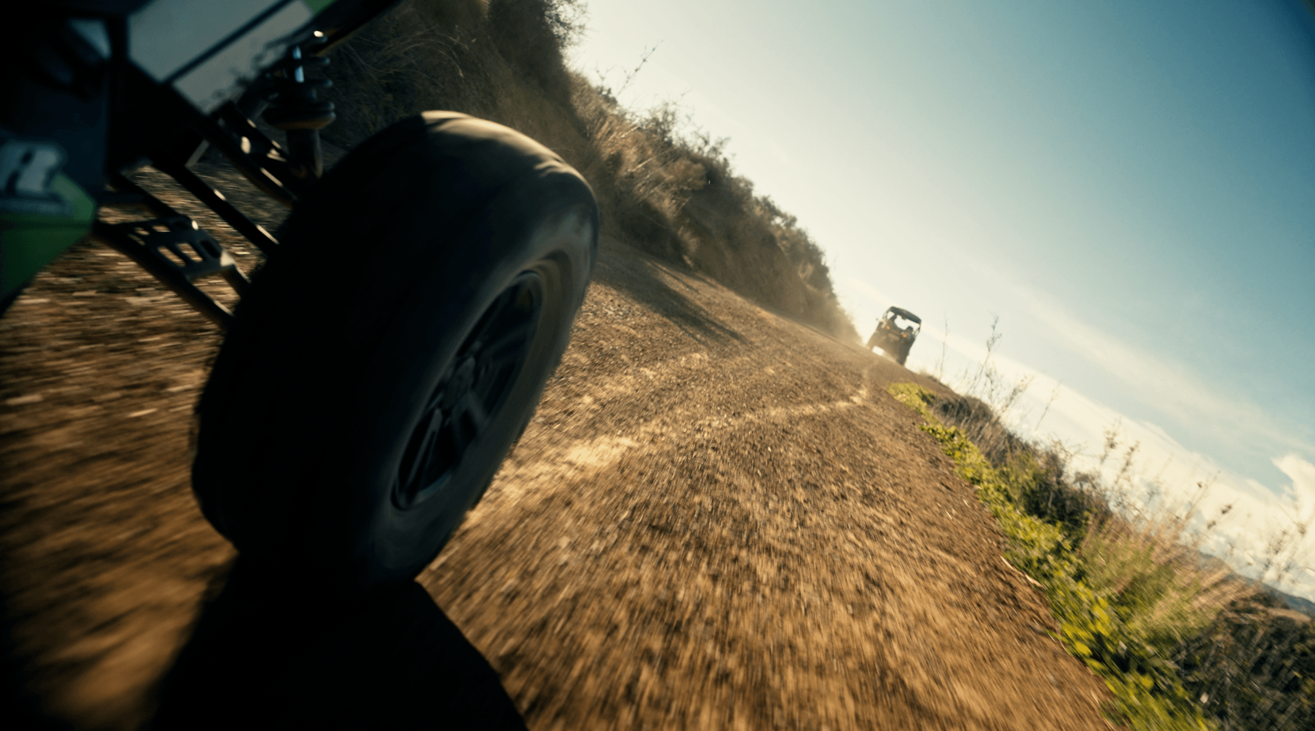 Off-road buggy wheel kicking up dust on rugged dirt trail