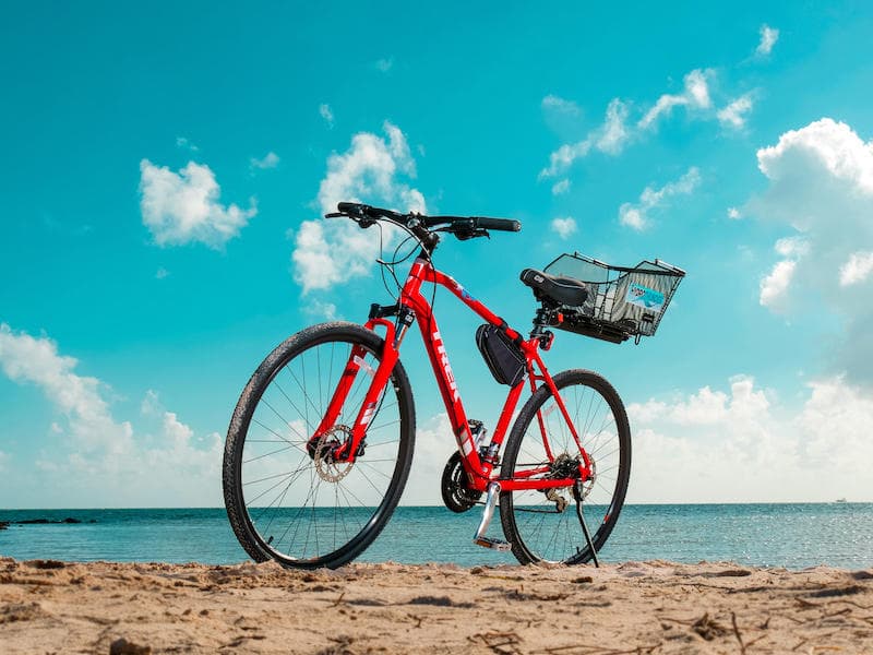 Red beach cruiser bike on sandy Key West shore under blue sky