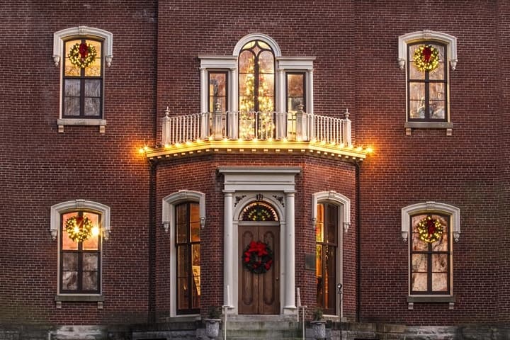 Brick manor entrance decorated with lights and wreaths, exterior