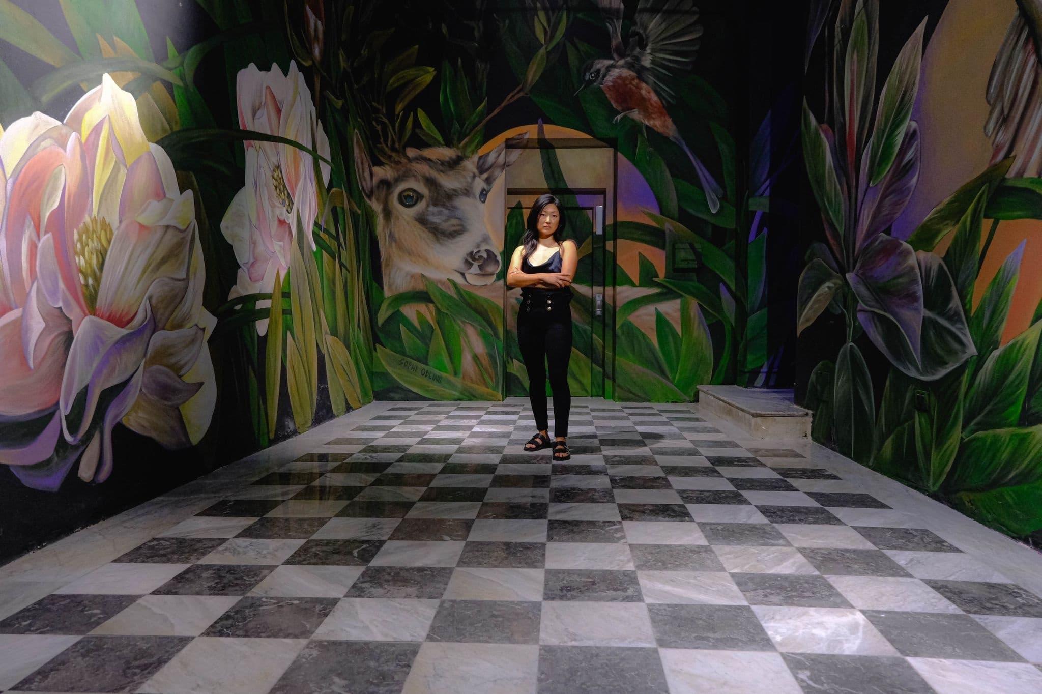 Person posing inside colorful indoor mural gallery with checkered floor