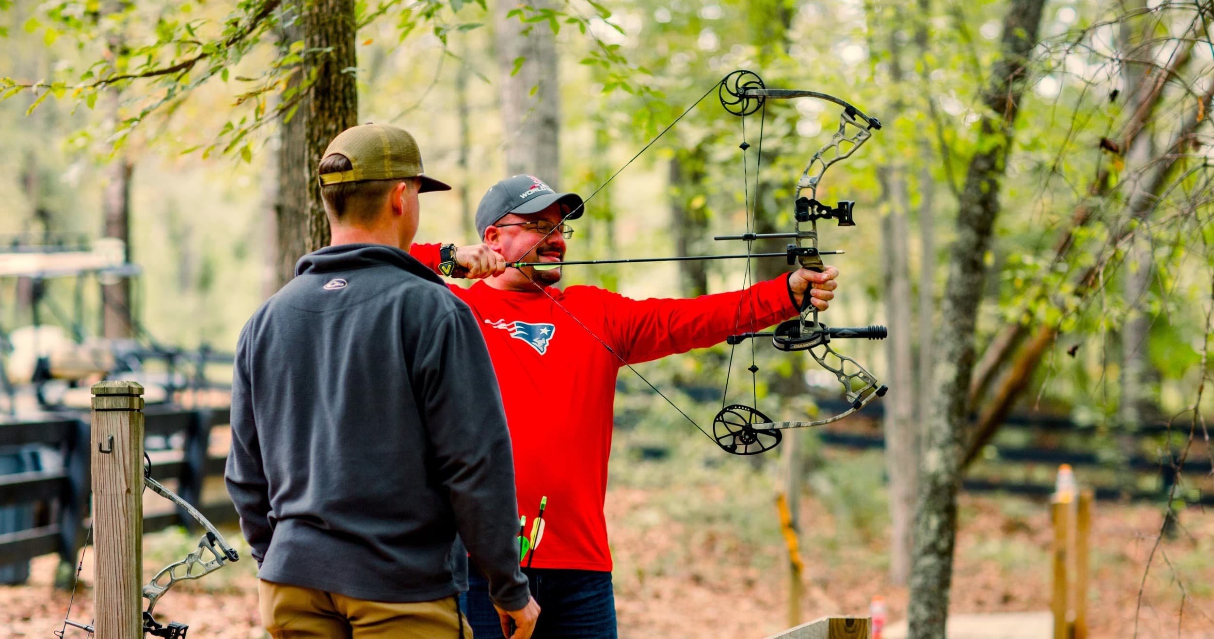 Instructor coaching target archery in wooded outdoor course