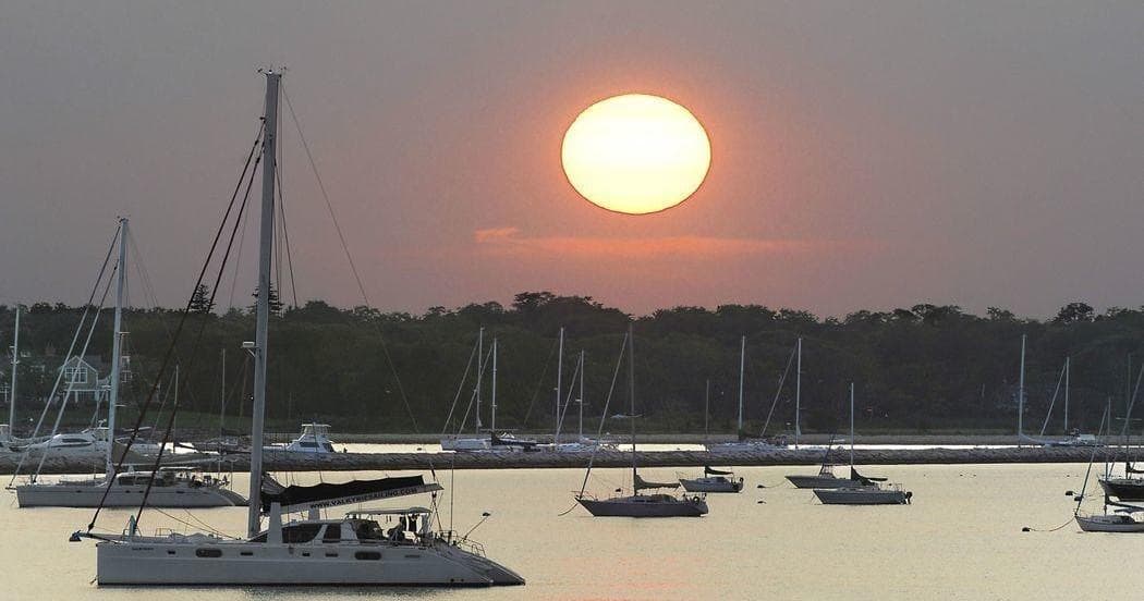 Sunset over harbor with moored sailboats and calm water