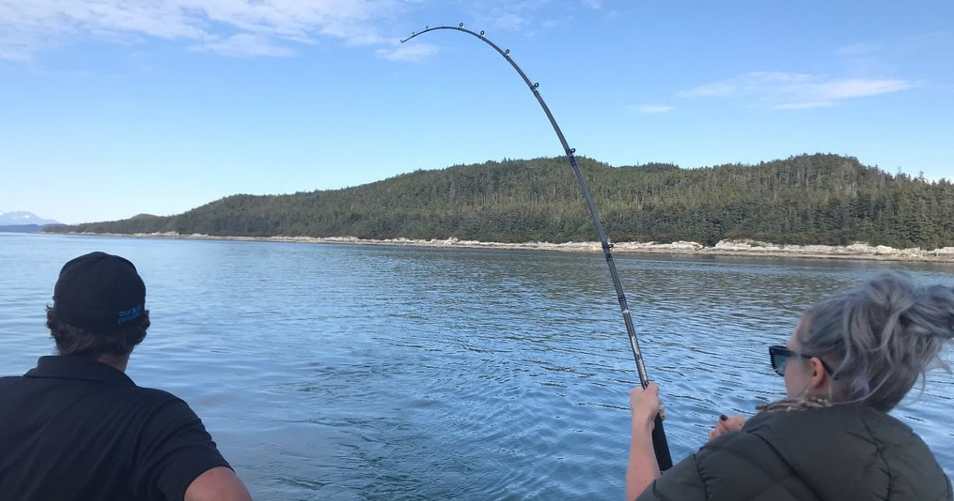 Anglers fighting a hooked fish from boat along coastal waters