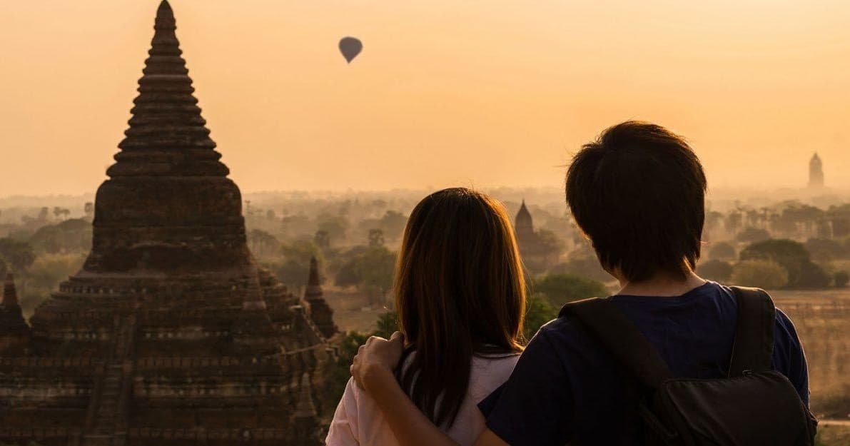 Couple watching temple sunset with hot air balloon over Bagan