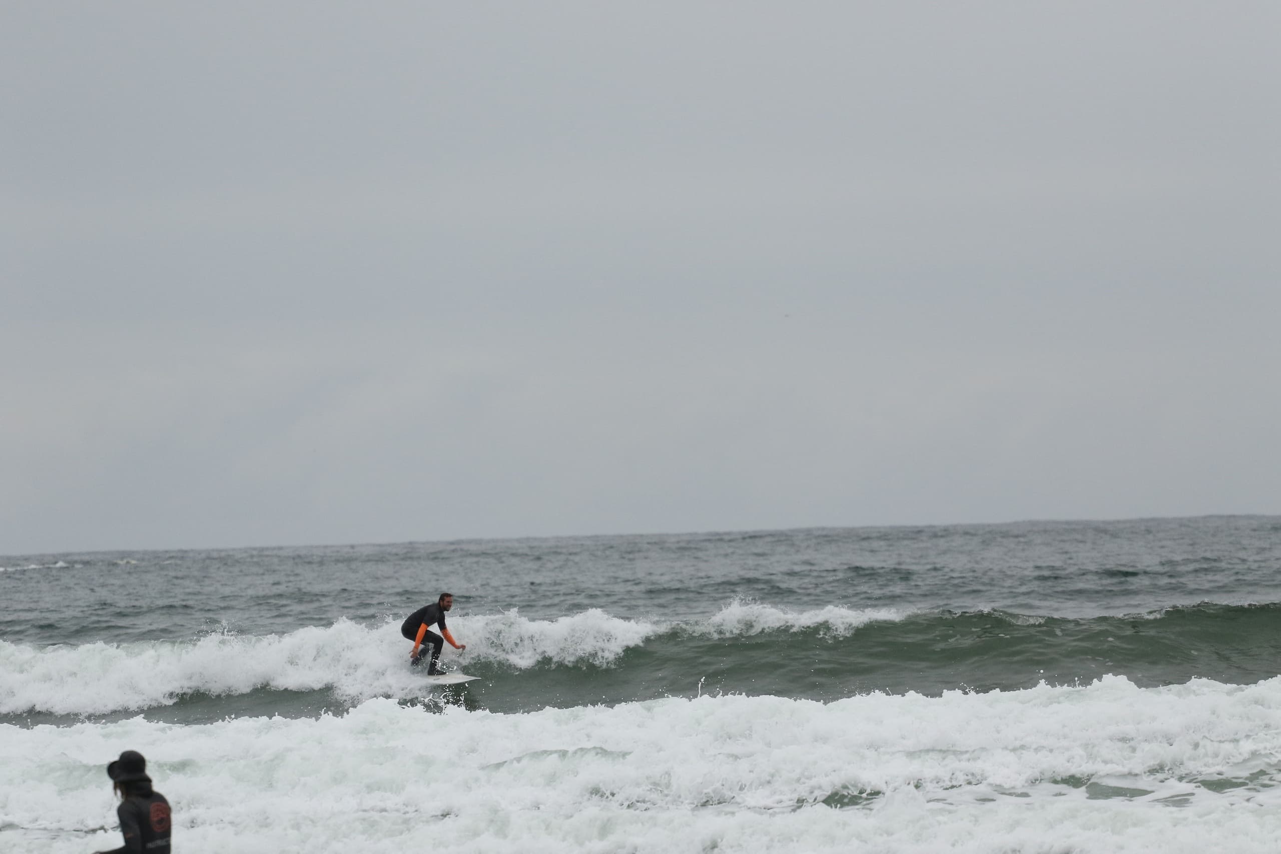 Surfer riding a breaking ocean wave near a rocky coastline