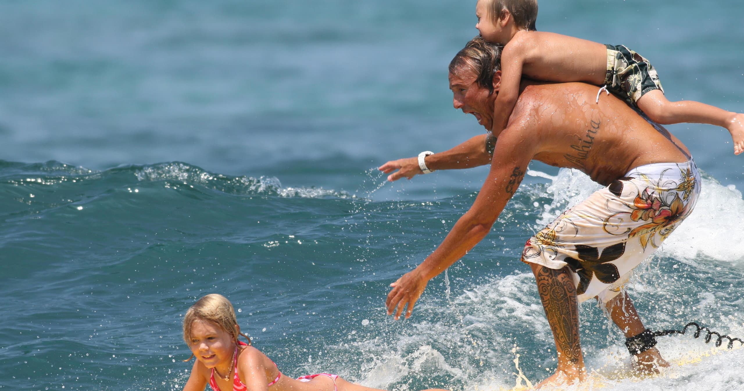 Family surfing with child on small coastal wave near shore