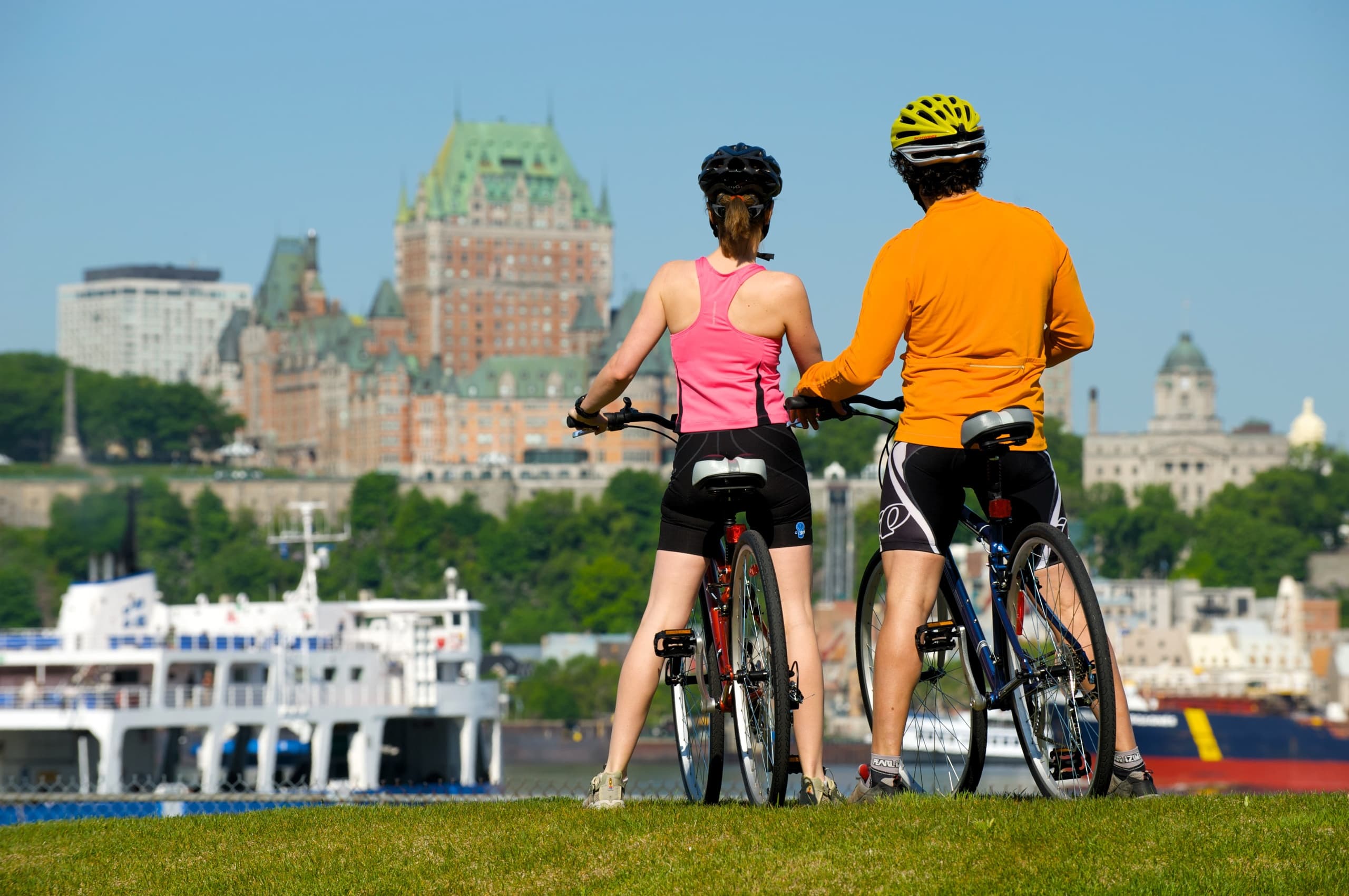 Couple cycling with city skyline view overlooking Quebec harbor