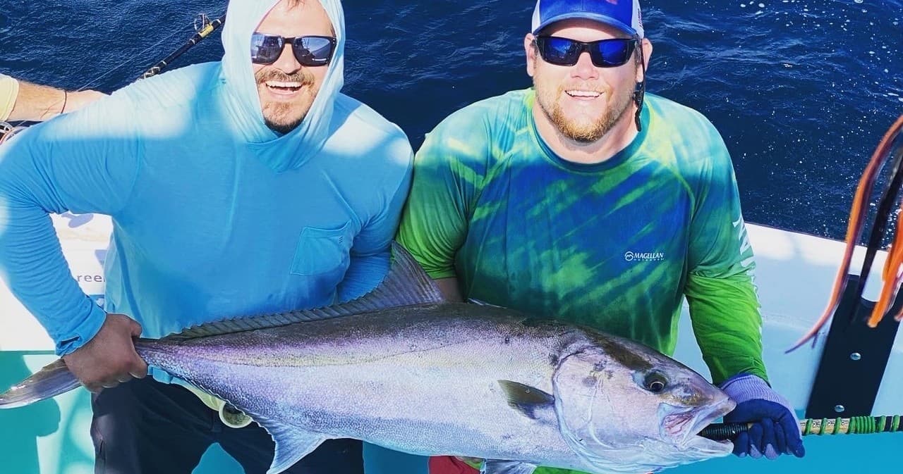 Two anglers proudly posing with giant tuna on charter boat deck