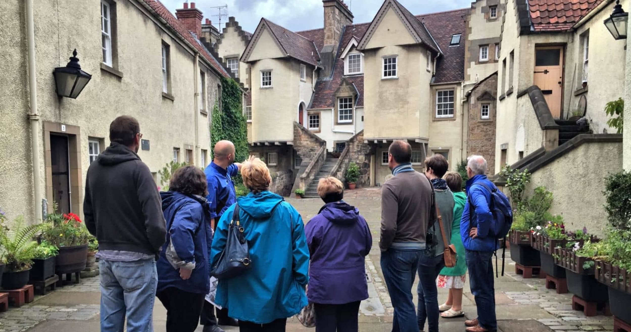 Guided walking tour group exploring narrow historic streets in Edinburgh
