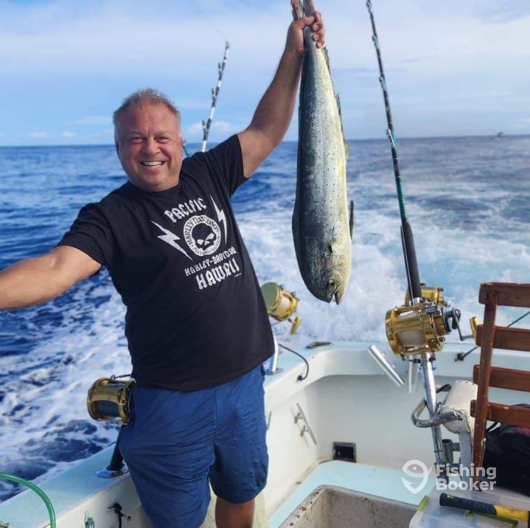 Angler posing with large mahi-mahi aboard sportfishing boat, Hawaii
