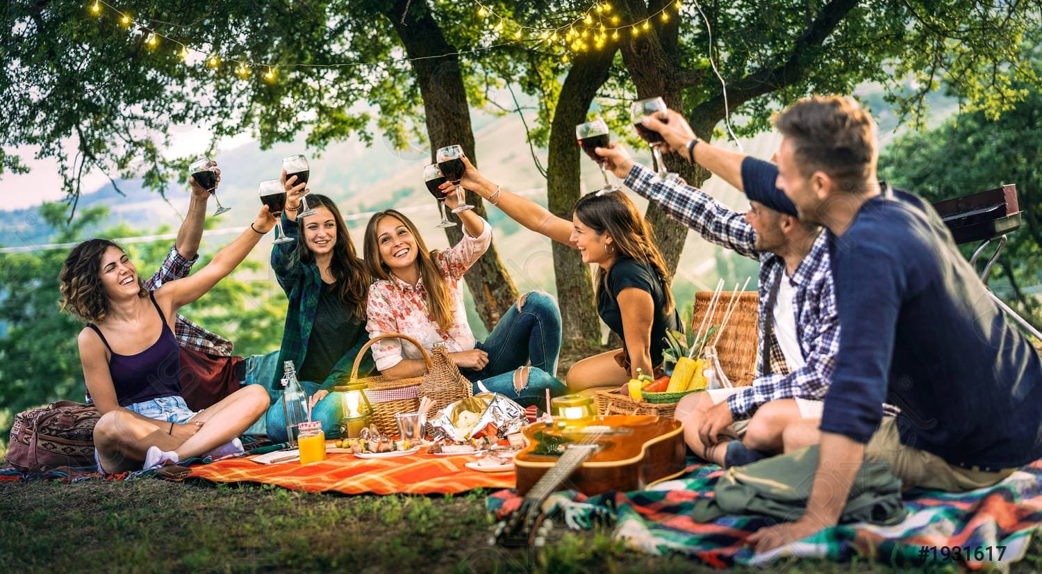 Friends picnic outdoors under trees sharing food and laughter