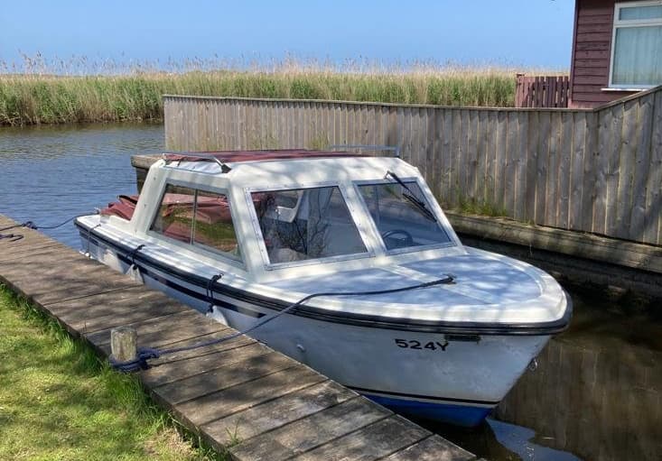 Small sheltered cabin boat moored at wooden dock in estuary