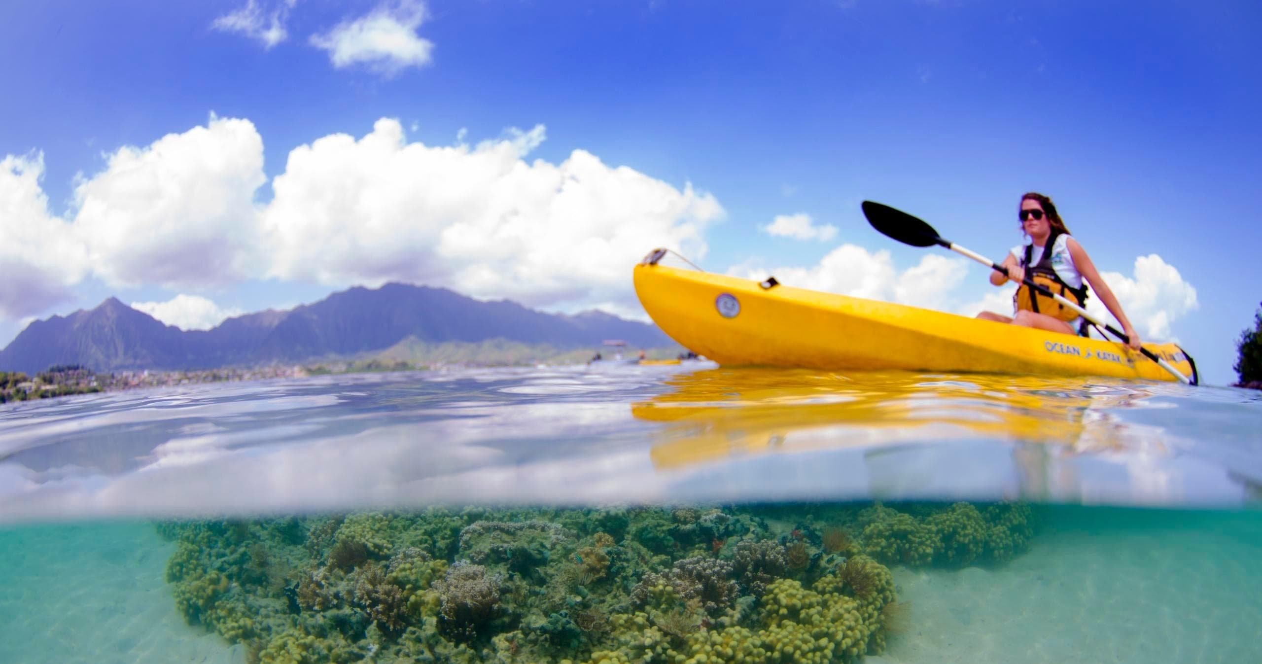 Paddler kayaking near coral reef in clear tropical waters