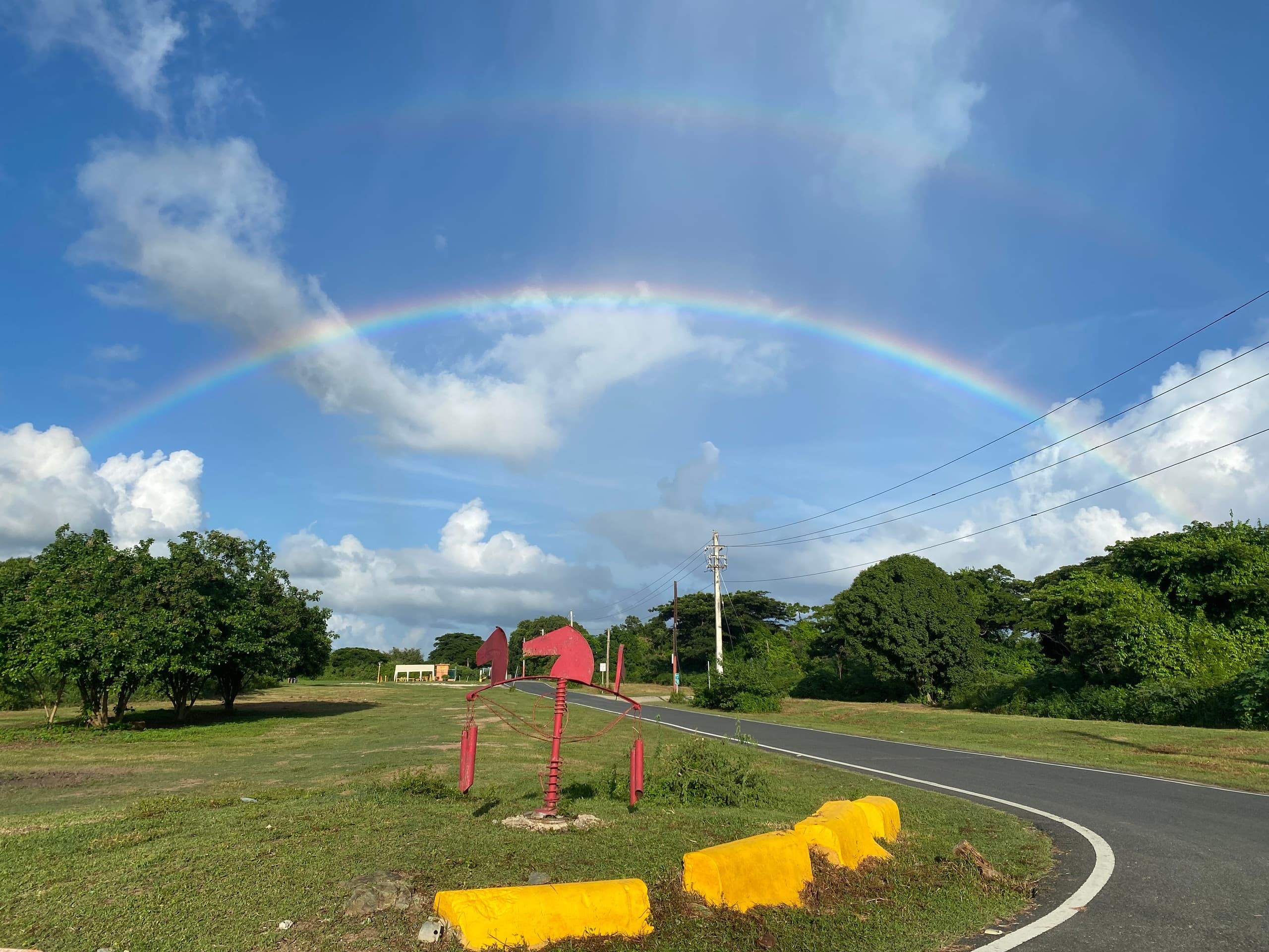 Double rainbow over scenic coastal road and green landscape